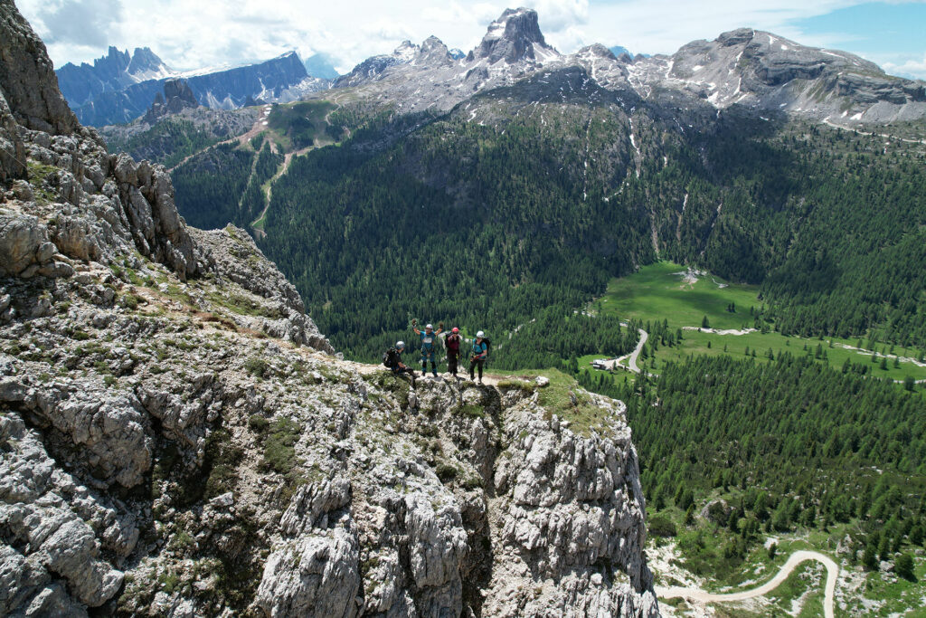 Cztery osoby na wypłaszczeniu skalnym, w tle zielona, porośnięta lasem dolina, a za nią górskie szczyty