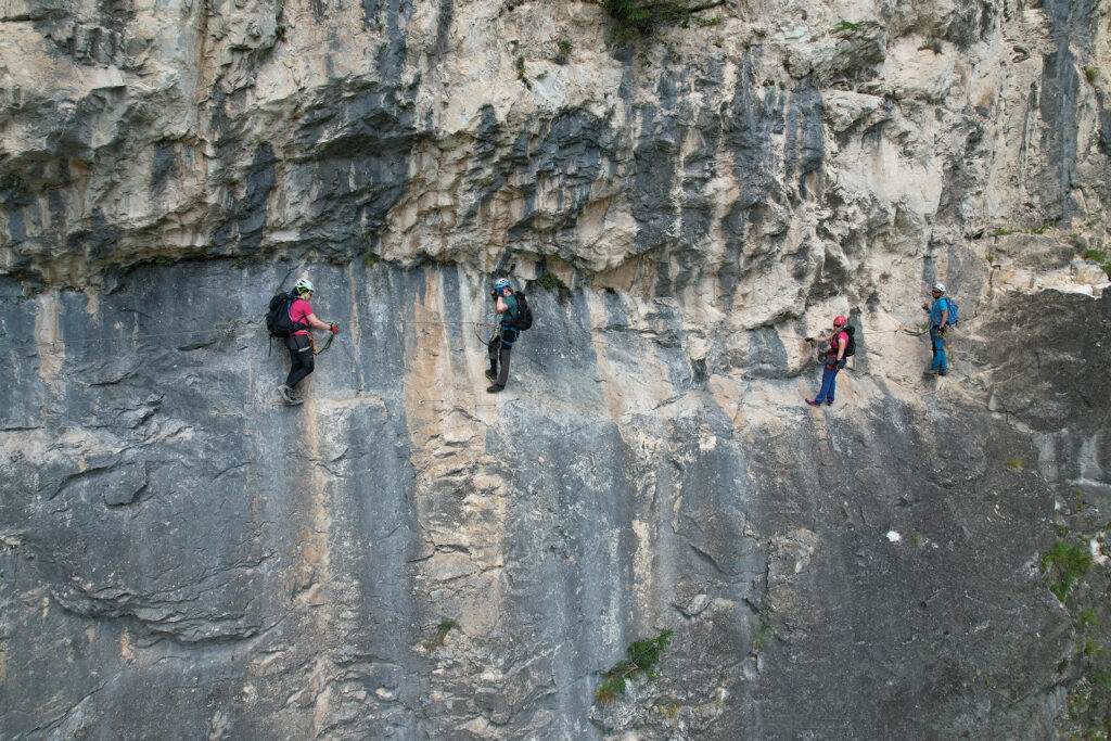 Cztery osoby wyglądają jak zawieszone na skale, tymczasem są przypięte do liny via ferrata